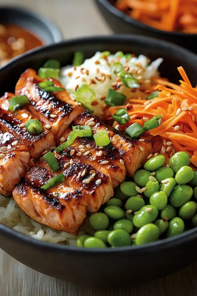 Asian-inspired burger bowl recipe with grilled salmon, edamame, shredded carrots, and sesame seeds.