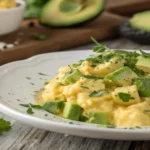 avocado scrambled eggs on a plate with herbs.