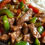 Close-up of sizzling pepper steak in a wok with bell peppers.